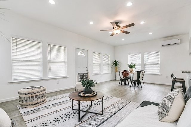 living room featuring hardwood / wood-style flooring, an AC wall unit, and ceiling fan