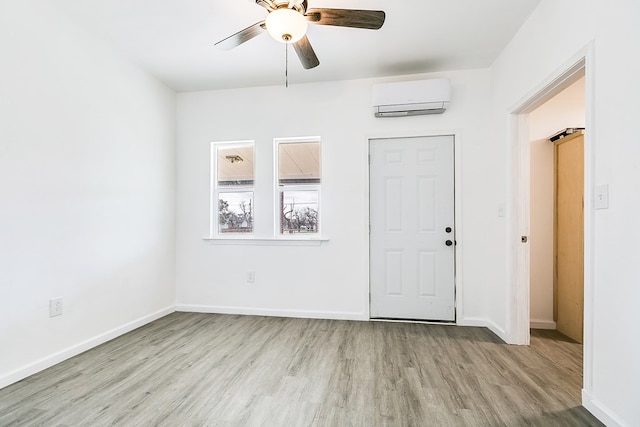 entrance foyer featuring ceiling fan, a wall mounted AC, and light hardwood / wood-style flooring