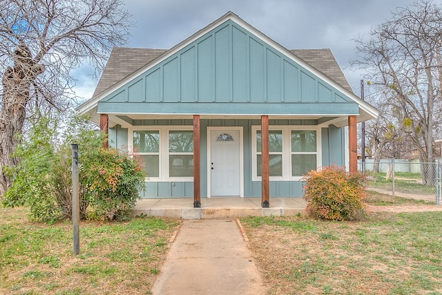 bungalow-style house featuring covered porch and a front yard