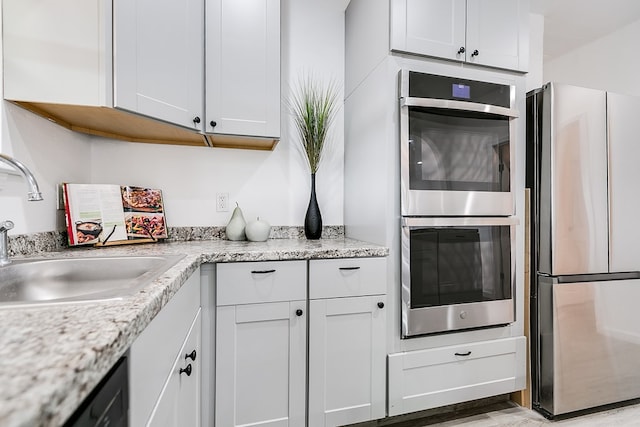 kitchen featuring light stone counters, sink, stainless steel appliances, and white cabinets