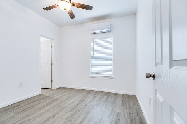 unfurnished room with ceiling fan, light wood-type flooring, and an AC wall unit