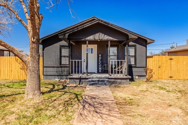 bungalow-style house with covered porch and fence