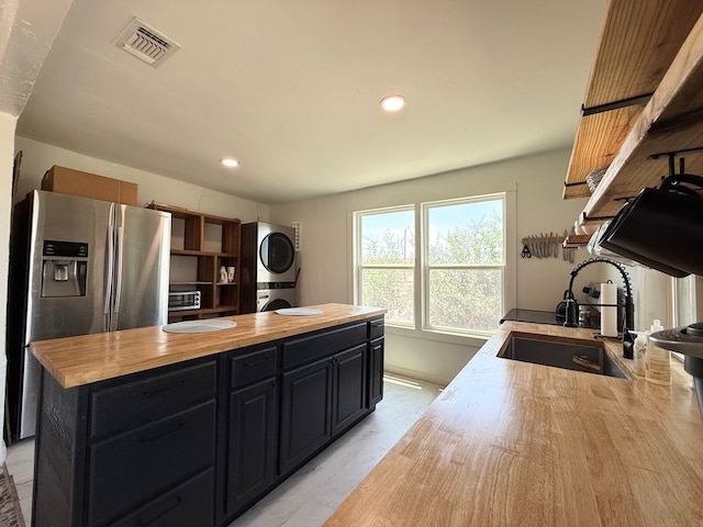 1702 Ellis St, San Angelo, TX 76905 - kitchen with a sink, stacked washing machine and dryer, wood counters, stainless steel fridge with ice dispenser, and dark cabinetry