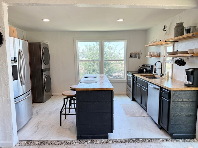 1702 Ellis St, San Angelo, TX 76905 - kitchen with stainless steel appliances, stacked washer / dryer, open shelves, a sink, and light marble finish flooring