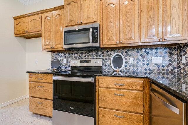 kitchen featuring appliances with stainless steel finishes, light tile patterned floors, decorative backsplash, and dark stone counters