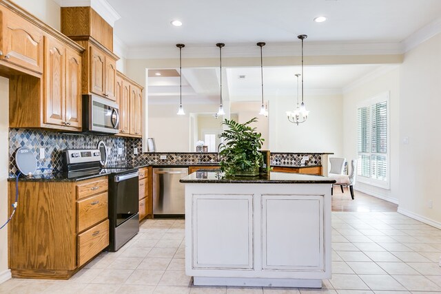 kitchen with crown molding, hanging light fixtures, appliances with stainless steel finishes, a kitchen island, and dark stone counters