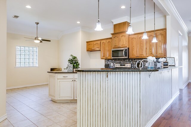 kitchen featuring crown molding, kitchen peninsula, decorative backsplash, and appliances with stainless steel finishes