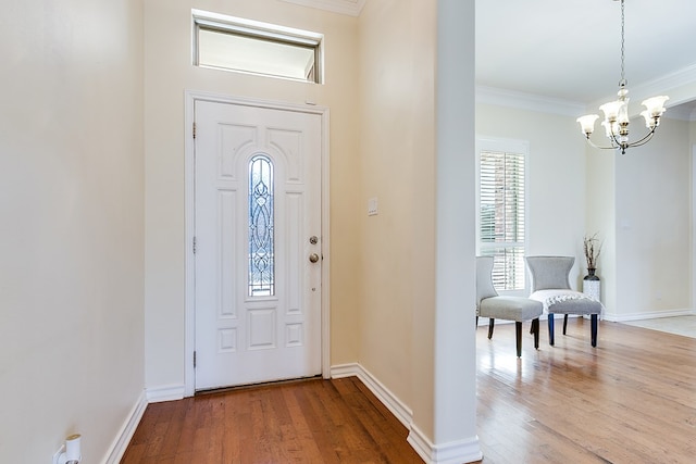 entrance foyer with ornamental molding, wood-type flooring, and a chandelier