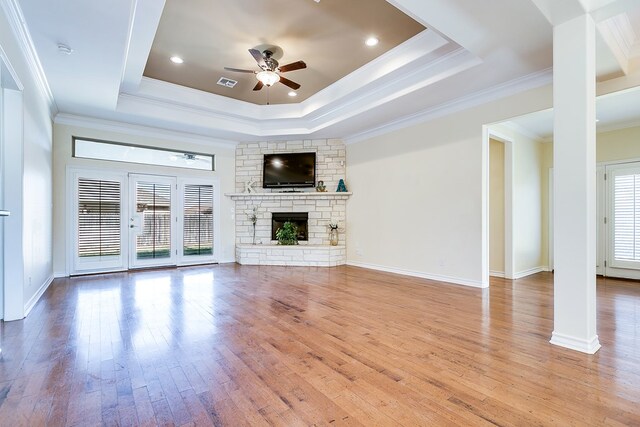 unfurnished living room with a raised ceiling, ceiling fan, crown molding, and a fireplace