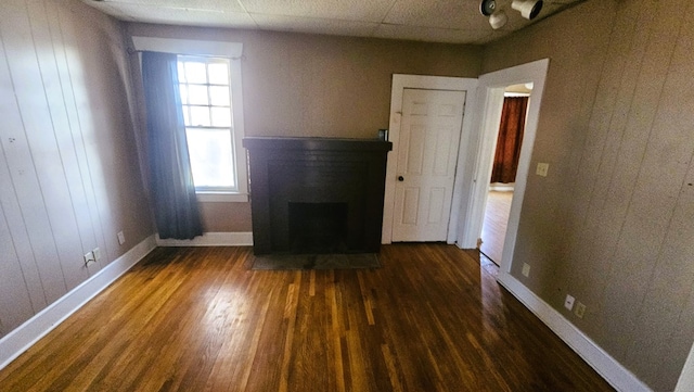 unfurnished living room featuring dark hardwood / wood-style flooring and wood walls