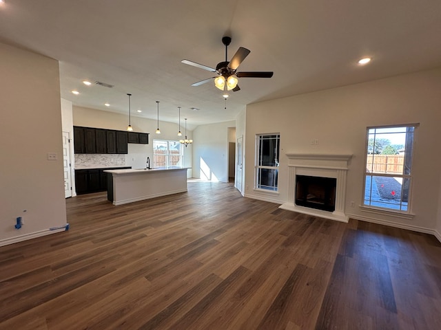 unfurnished living room featuring lofted ceiling, dark hardwood / wood-style floors, sink, and ceiling fan