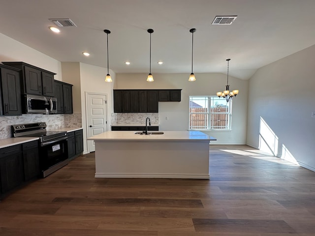 kitchen with dark wood-type flooring, sink, appliances with stainless steel finishes, an island with sink, and pendant lighting