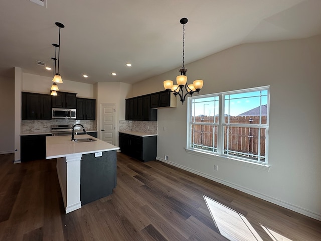 kitchen featuring sink, an inviting chandelier, a center island with sink, stainless steel appliances, and decorative backsplash