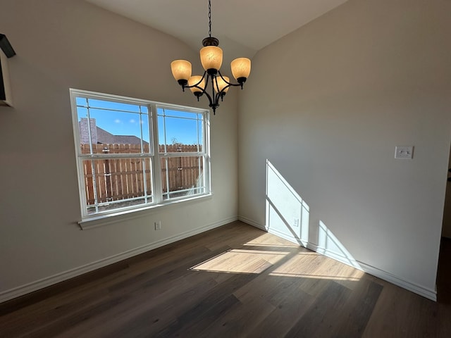 unfurnished room featuring lofted ceiling, hardwood / wood-style flooring, and an inviting chandelier