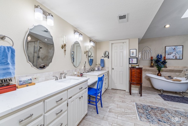 full bathroom featuring a textured ceiling, a shower with shower door, vanity, visible vents, and tile walls