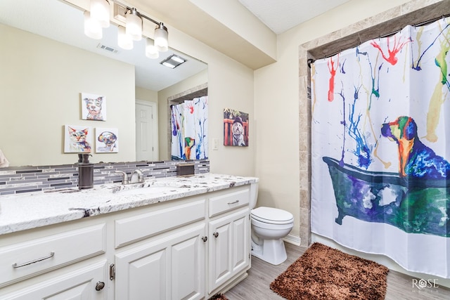 full bath featuring visible vents, backsplash, toilet, vanity, and wood finished floors