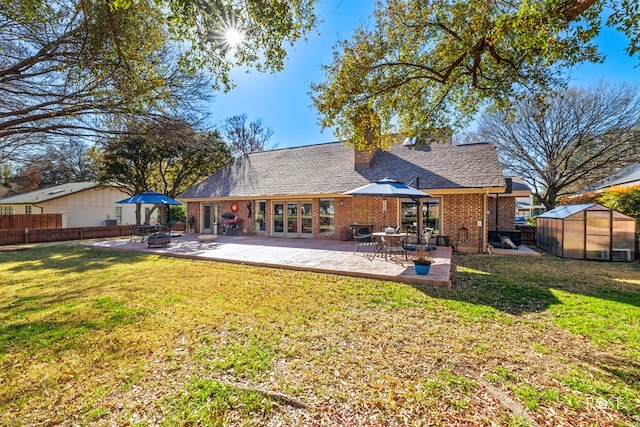 rear view of house with an outbuilding, fence, a lawn, a patio area, and an exterior structure