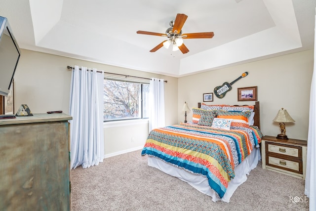 bedroom featuring ceiling fan, a tray ceiling, carpet, and baseboards