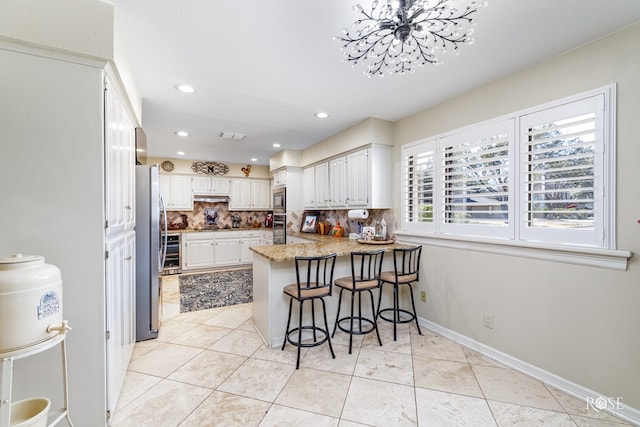 kitchen featuring a peninsula, light tile patterned floors, appliances with stainless steel finishes, and decorative backsplash