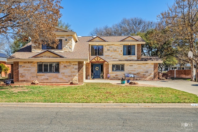 traditional-style house with roof with shingles, fence, stone siding, driveway, and a front lawn