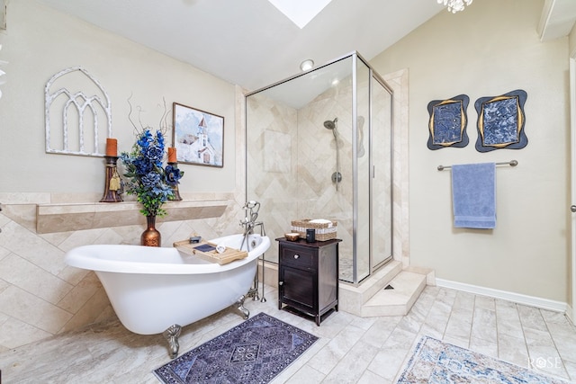 bathroom with a stall shower, a skylight, a freestanding tub, and tile walls