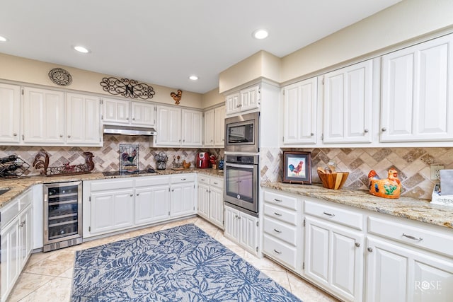 kitchen featuring light tile patterned floors, beverage cooler, stainless steel appliances, under cabinet range hood, and white cabinetry