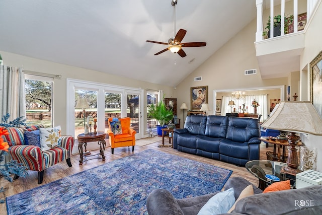 living room featuring ceiling fan with notable chandelier, high vaulted ceiling, wood finished floors, and visible vents