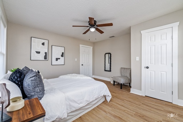 bedroom featuring ceiling fan, a textured ceiling, and light wood-type flooring