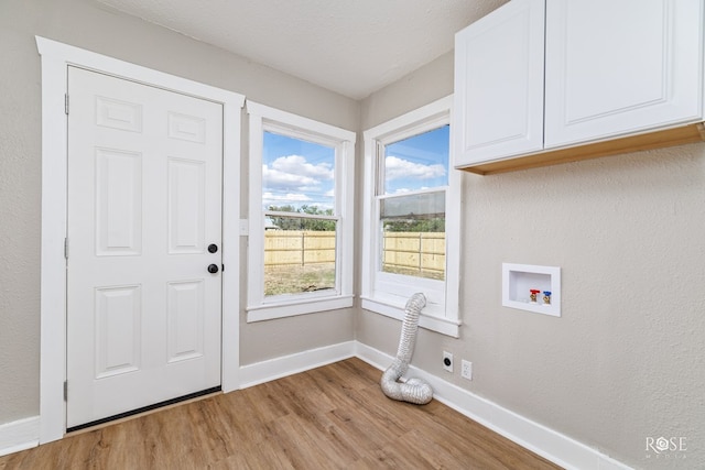 clothes washing area with light hardwood / wood-style flooring, cabinets, washer hookup, a textured ceiling, and hookup for an electric dryer