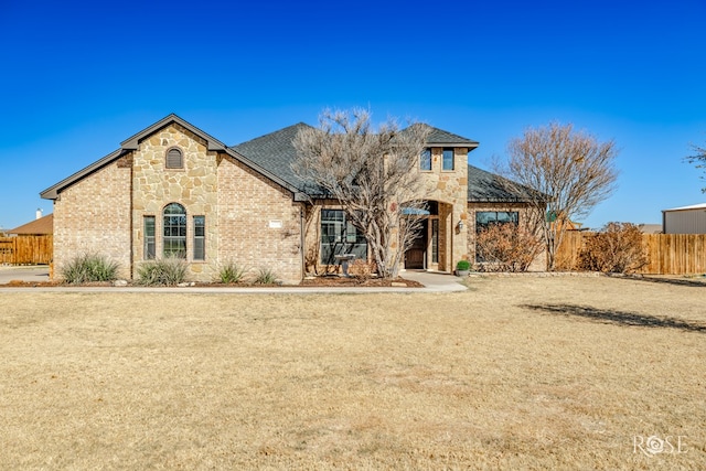 view of front facade with stone siding, brick siding, and fence