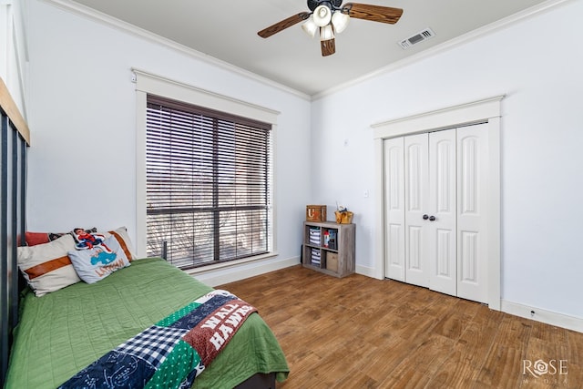 bedroom featuring visible vents, wood finished floors, baseboards, and ornamental molding