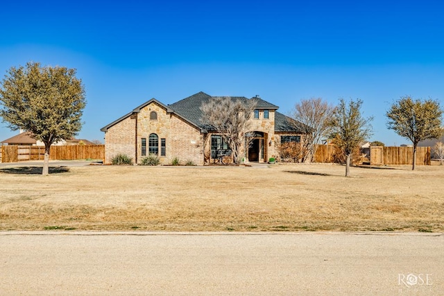 french country inspired facade with stone siding and fence