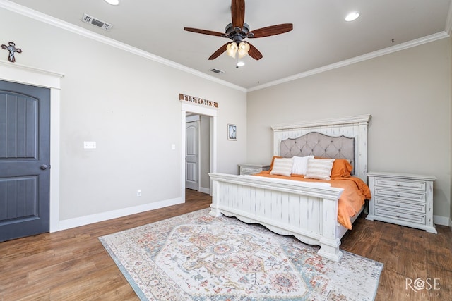 bedroom featuring visible vents, baseboards, wood finished floors, and ornamental molding