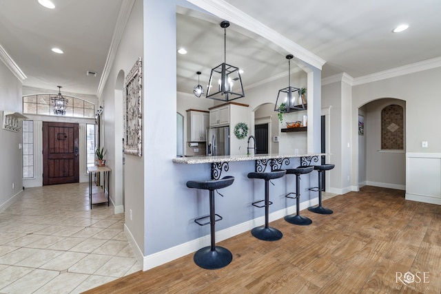 kitchen featuring arched walkways, stainless steel refrigerator with ice dispenser, and ornamental molding