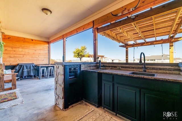 interior space featuring a sink, dark countertops, concrete flooring, and wooden walls