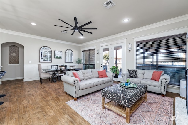 living area with wood finished floors, visible vents, and ornamental molding