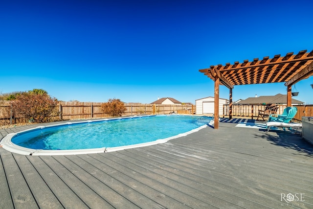 view of pool with a storage unit, an outbuilding, a pergola, a fenced backyard, and a wooden deck