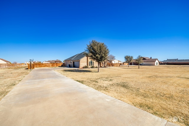 view of yard with a residential view, concrete driveway, a garage, and fence