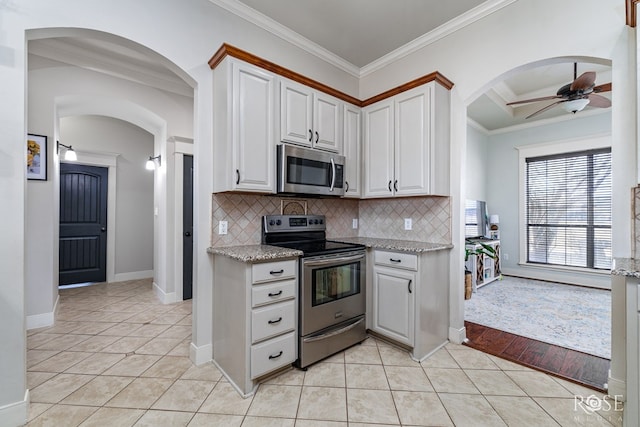 kitchen with crown molding, light tile patterned floors, a ceiling fan, and appliances with stainless steel finishes