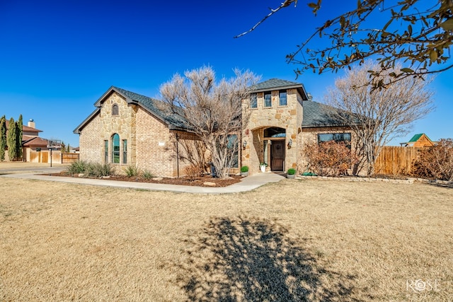 view of front facade with brick siding, stone siding, and fence