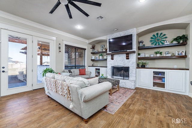 living area featuring visible vents, wood finished floors, and ornamental molding