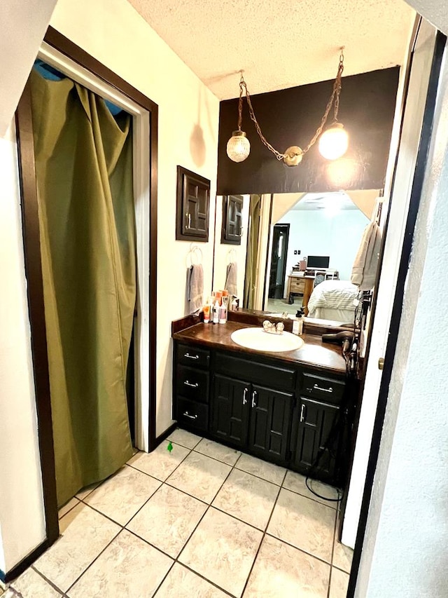 bathroom with ensuite bathroom, a textured ceiling, tile patterned flooring, and vanity