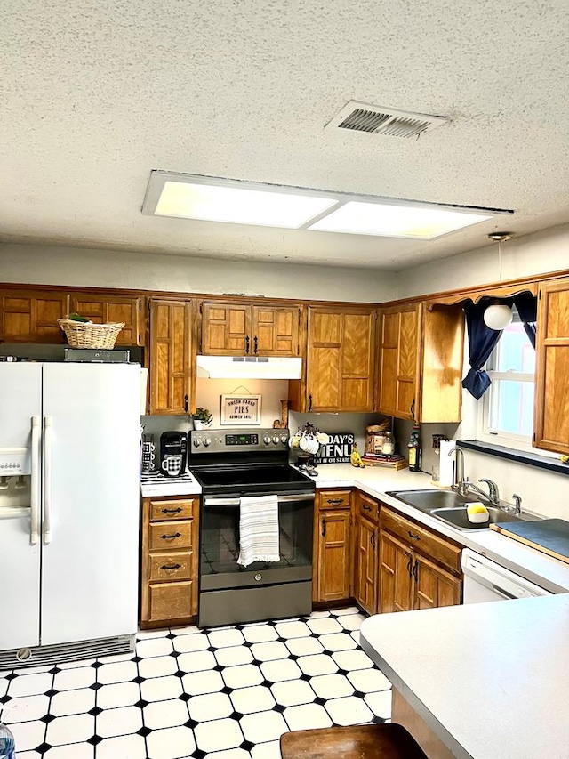 kitchen with white appliances, brown cabinetry, light countertops, under cabinet range hood, and a sink