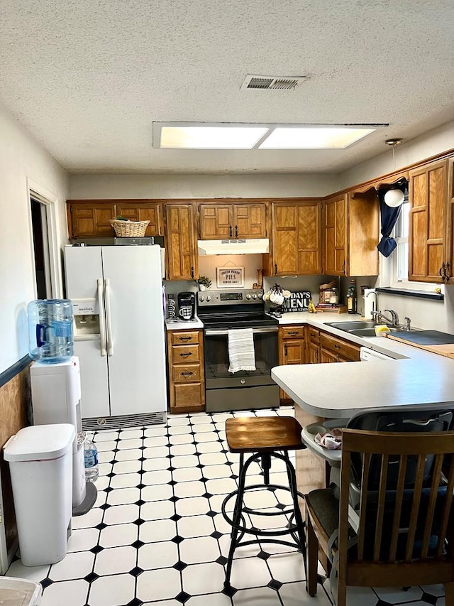 kitchen with under cabinet range hood, white refrigerator with ice dispenser, electric stove, light countertops, and brown cabinetry