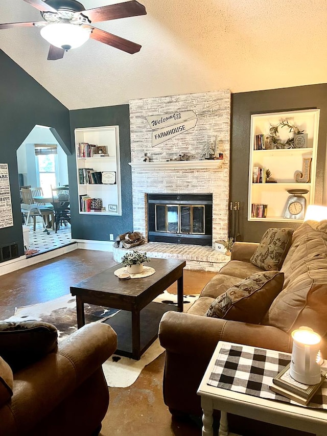 living room with a textured ceiling, built in shelves, visible vents, vaulted ceiling, and a brick fireplace