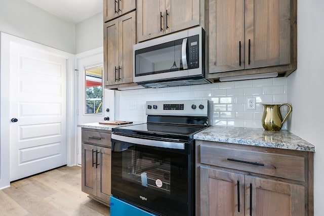 kitchen with light stone counters, electric range oven, decorative backsplash, and light hardwood / wood-style floors