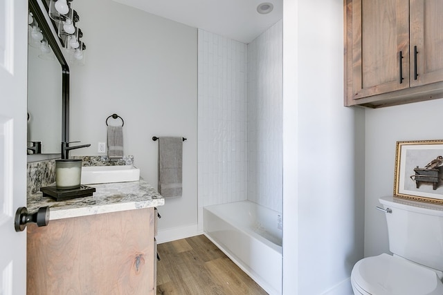 full bathroom with vanity, tiled shower / bath, hardwood / wood-style flooring, and toilet