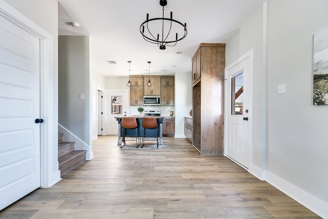 kitchen with a kitchen island, a breakfast bar, pendant lighting, a chandelier, and light hardwood / wood-style floors