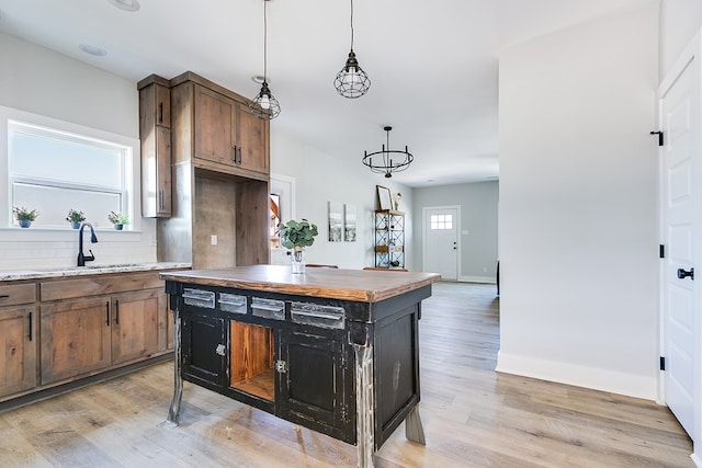 kitchen with pendant lighting, a center island, light hardwood / wood-style floors, and tasteful backsplash