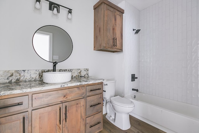 full bathroom with vanity, hardwood / wood-style floors, tiled shower / bath combo, and toilet